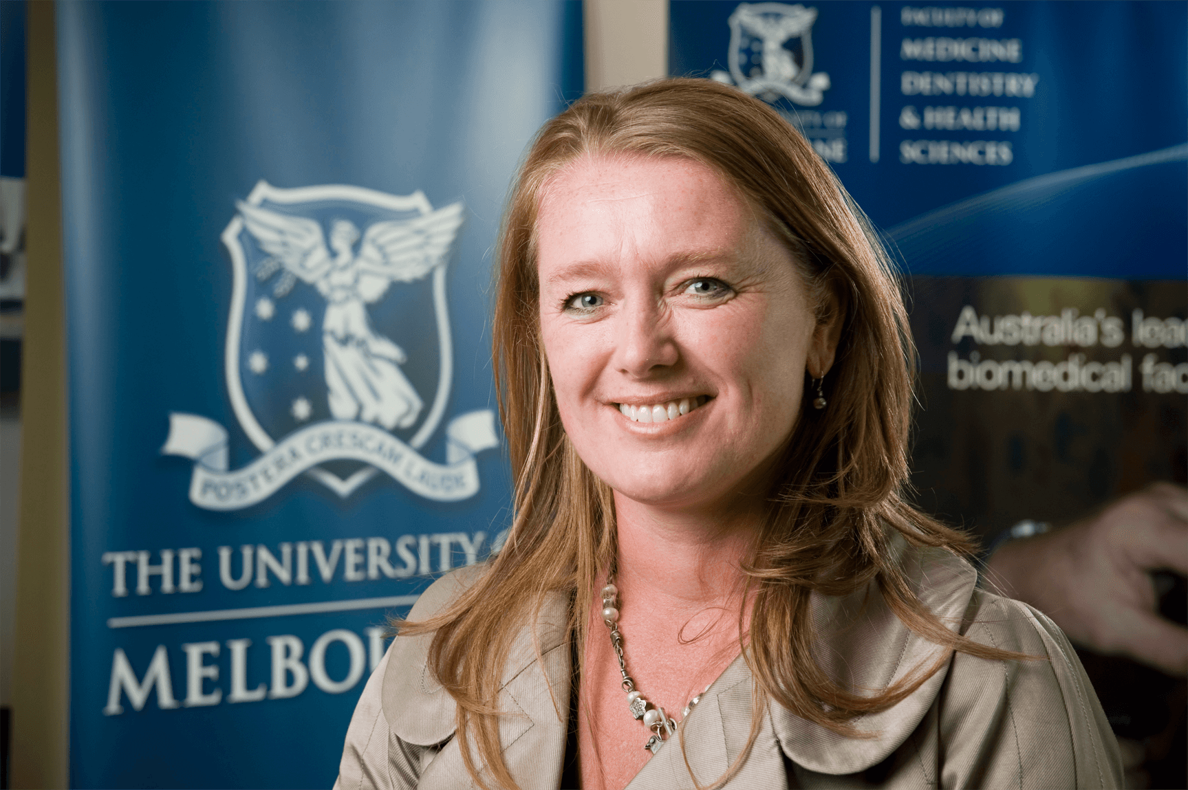 Professor Elizabeth Waters, DPhil, FPH 1966 – 2015 Prof Waters standing in front of Melbourne Uni banner