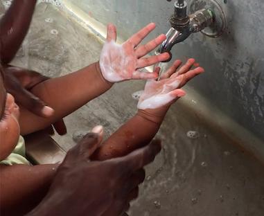 child having their hands washed
