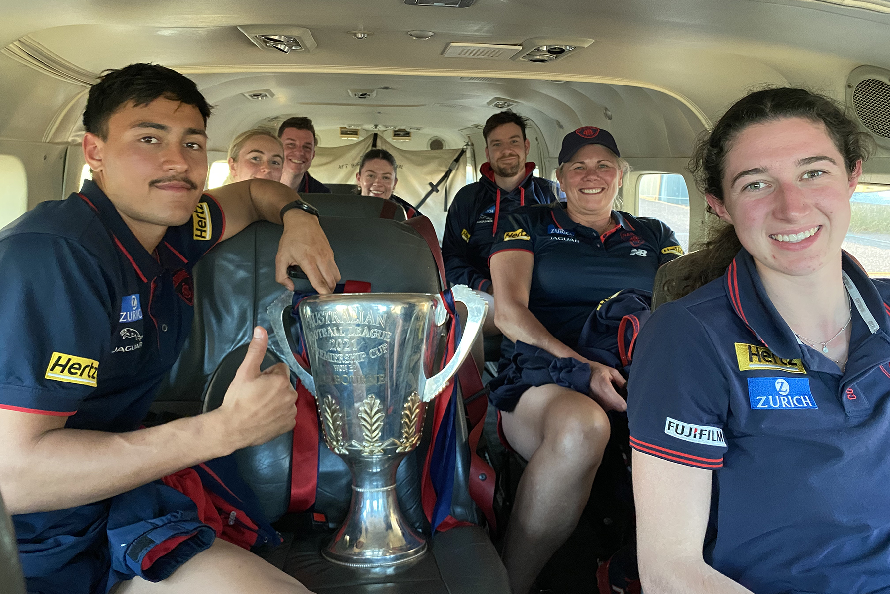 MFC crew on the plane with the premiership cup on the seat