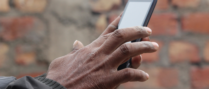 Brown Male hand typing on smart Phone