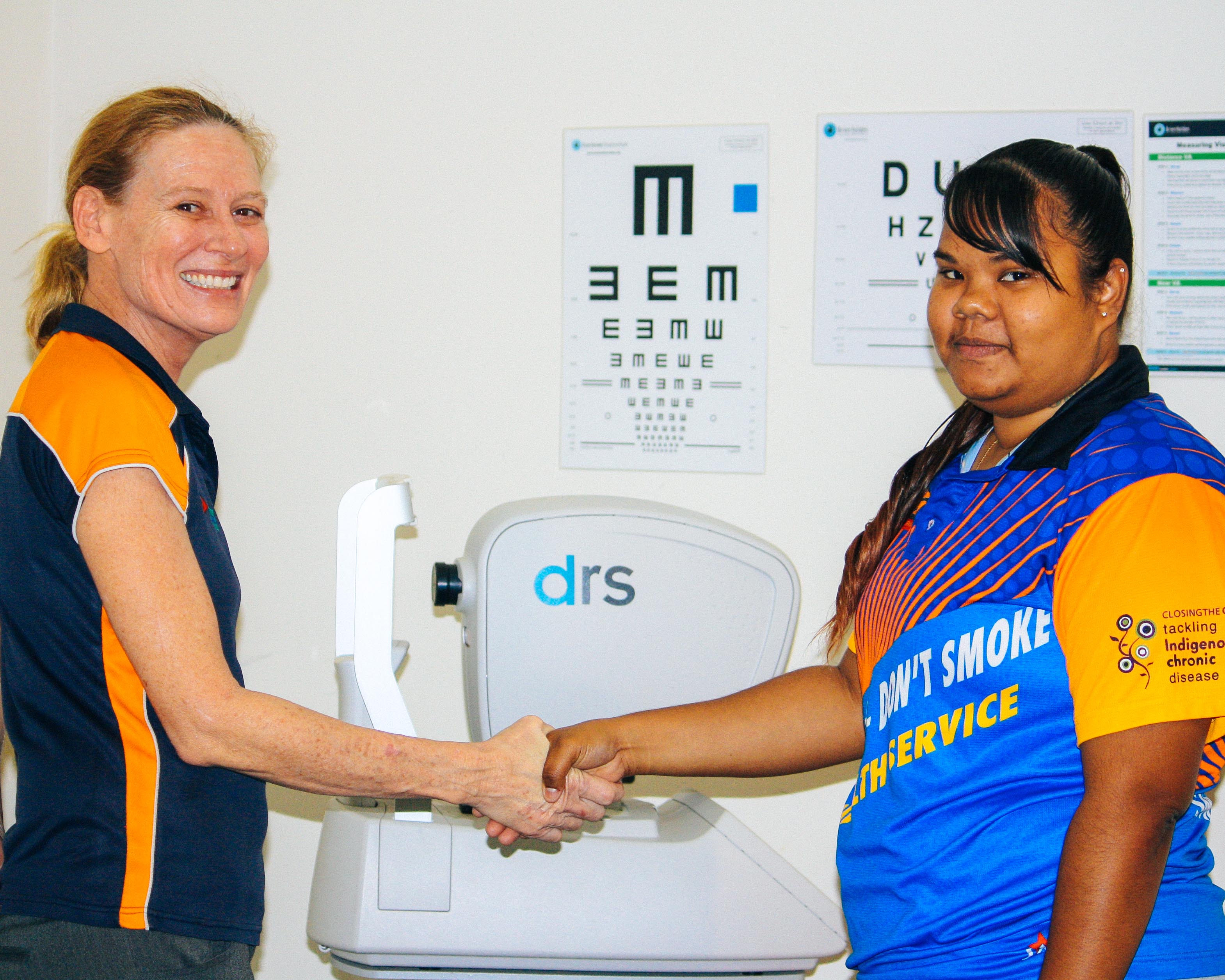 Tania and Karliy shaking hands in front of a retinal camera