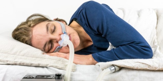 Woman lying in bed using cpap machine