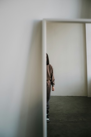 Photo of a the reflection of a woman on a mirror. We can only see half of her body, and not her face