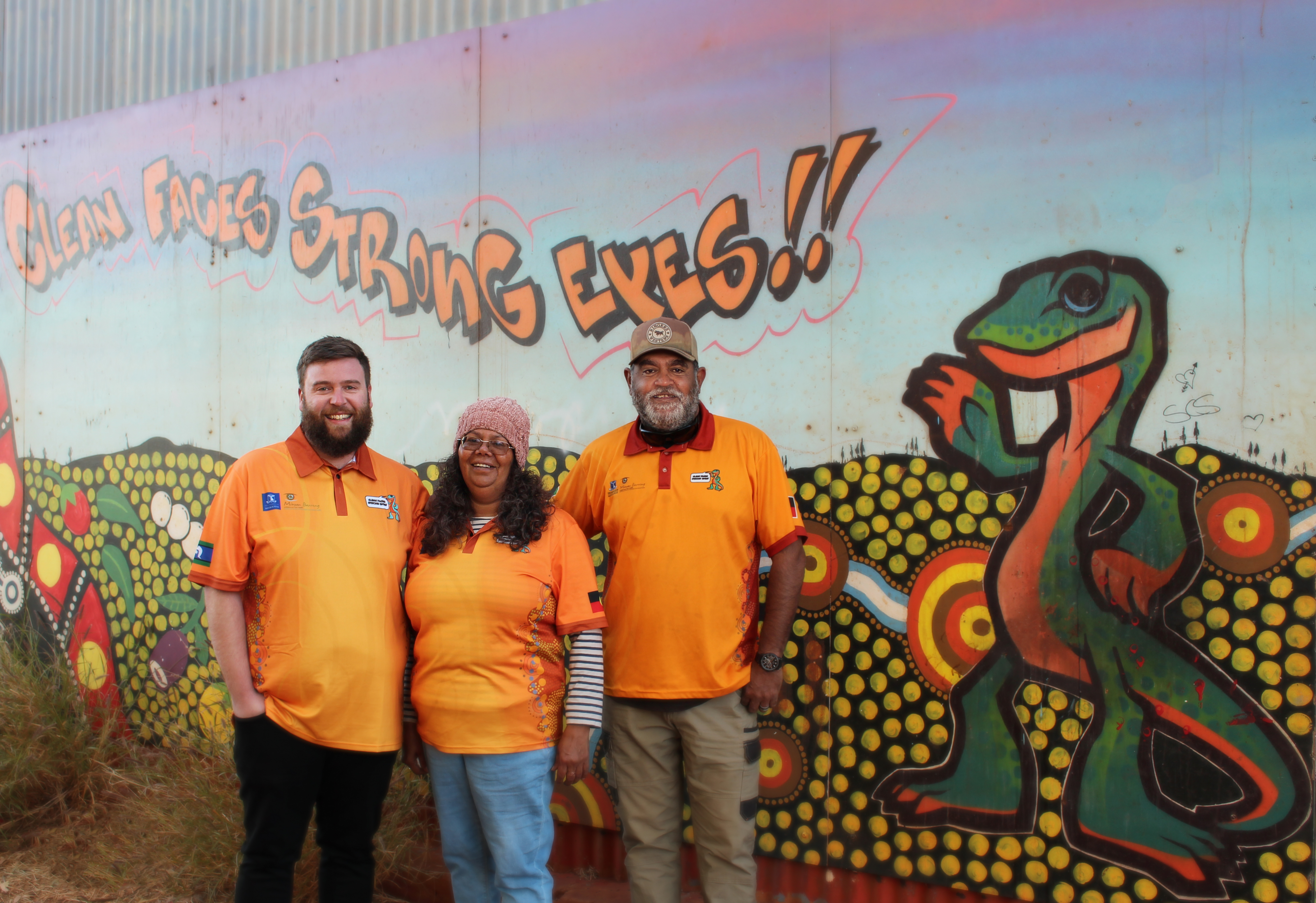 Nick, Lesley and Walter standing together in front of a colourful painted mural