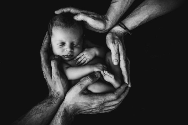 Baby held by four hands