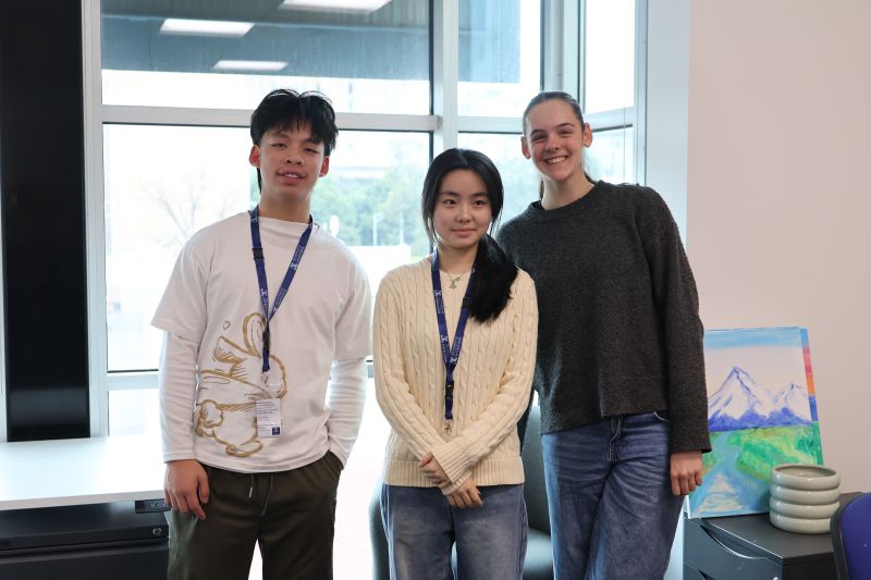 Three year 10 students standing in an office smiling at the camera. 