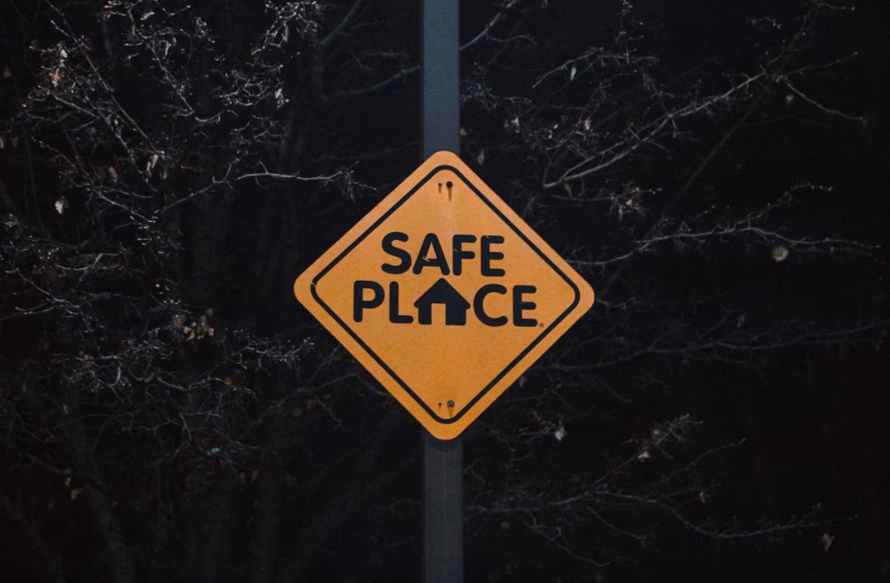 A road sign that reads "safe place". The "A" in "place" is shaped like a home
